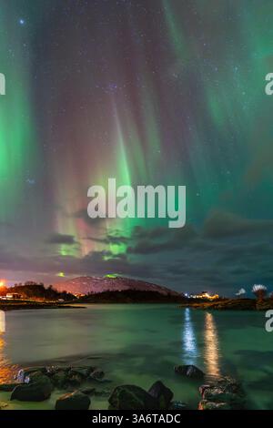 Belle Aurora Borealis sur la maison sur l'île de Kvaløya, dansant les aurores boréales avec la lumière verte, les grèves rouges et violettes, les rayons colorés clairs Banque D'Images