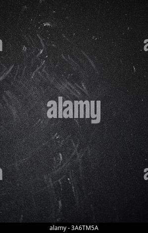 Surface texturée foncée avec des résidus de craie et des rayures, montrant des signes d'usure et d'âge, créant un arrière-plan grossier et abstrait Banque D'Images
