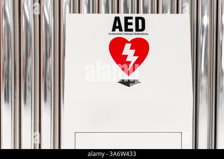 Vue d'ensemble d'un défibrillateur de sauvetage. Défibrillateur automatisé externe (DAE) portable fixé au mur dans les toilettes publiques de l'aéroport. Banque D'Images