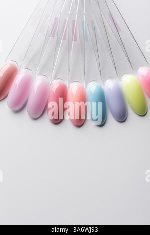 Tons de vernis à ongles pastel dans des tons verts, jaunes, lilas, bleus et roses sur un fond clair. Échantillons de pointes d'ongles dans différentes couleurs vives. Banque D'Images