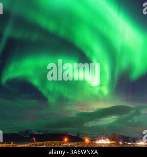 Belle Aurora Borealis sur la maison sur l'île de Kvaløya, dansant les aurores boréales avec la lumière verte, les grèves rouges et violettes, les rayons colorés clairs Banque D'Images