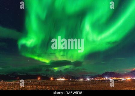 Belle Aurora Borealis sur la maison sur l'île de Kvaløya, dansant les aurores boréales avec la lumière verte, les grèves rouges et violettes, les rayons colorés clairs Banque D'Images