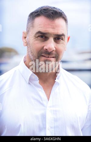 Portrait homme caucasien souriant avec les cheveux bruns courts et la barbe debout près de yachts de luxe. Banque D'Images