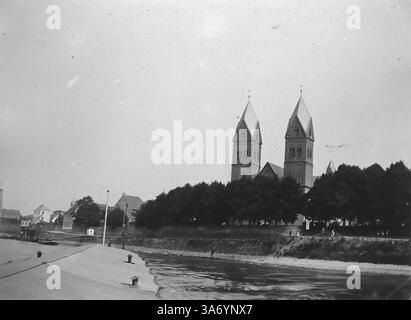 Le bâtiment principal de l'image est la basilique de préparé Castor, une église romane située à Coblence, en Allemagne, près du Rhin. Il se distingue par ses tours jumelles avec des toits pointus et des croix au sommet, ce qui en fait un point de repère emblématique dans la région. L'église date du IXe siècle et a une signification historique comme l'une des plus anciennes églises de Coblence. D’après une collection de photographies d’une tournée européenne familiale qui s’est déroulée en 1899. Les photographies originales étaient d'environ 3 ½ x 2 ½ pouces. Banque D'Images