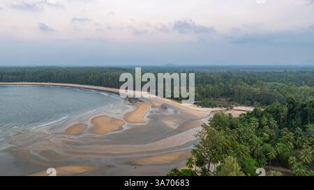 C'est une belle image de coucher de soleil sur l'océan, avec une petite île ou masse terrestre au premier plan. Les teintes dorées du soleil se fondent harmonieusement en t Banque D'Images