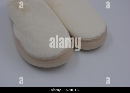 Belles et insolites choses pour femmes, chaussures de maison de tous les jours. Pantoufles douces chaudes blanches en fourrure épaisse synthétique avec semelles brunes épaisses et beiges. Banque D'Images