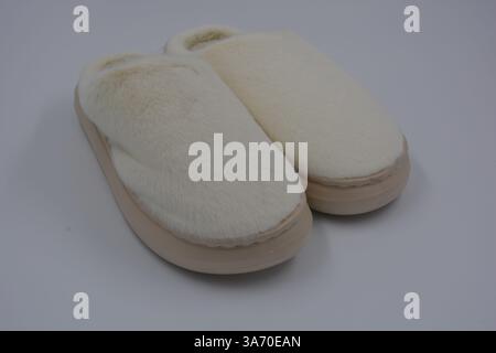 Belles et insolites choses pour femmes, chaussures de maison de tous les jours. Pantoufles douces chaudes blanches en fourrure épaisse synthétique avec semelles brunes épaisses et beiges. Banque D'Images