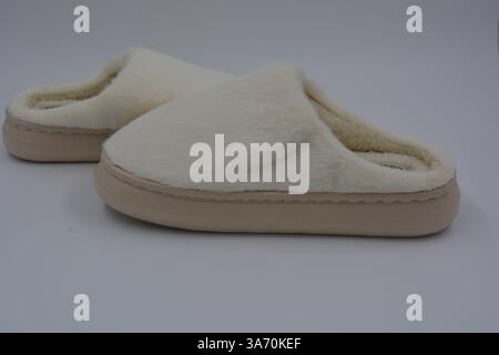 Belles et insolites choses pour femmes, chaussures de maison de tous les jours. Pantoufles douces chaudes blanches en fourrure épaisse synthétique avec semelles brunes épaisses et beiges. Banque D'Images