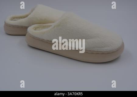 Belles et insolites choses pour femmes, chaussures de maison de tous les jours. Pantoufles douces chaudes blanches en fourrure épaisse synthétique avec semelles brunes épaisses et beiges. Banque D'Images