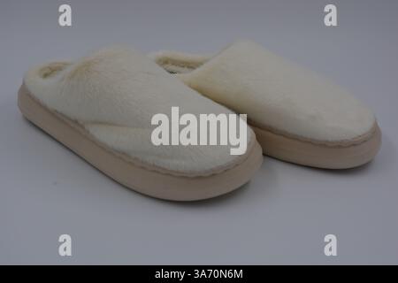 Belles et insolites choses pour femmes, chaussures de maison de tous les jours. Pantoufles douces chaudes blanches en fourrure épaisse synthétique avec semelles brunes épaisses et beiges. Banque D'Images