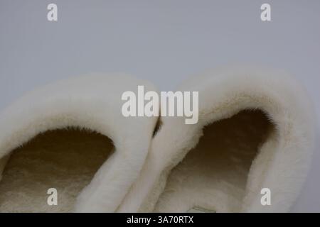 Belles et insolites choses pour femmes, chaussures de maison de tous les jours. Pantoufles douces chaudes blanches en fourrure épaisse synthétique avec semelles brunes épaisses et beiges. Banque D'Images