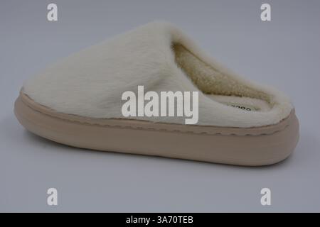 Belles et insolites choses pour femmes, chaussures de maison de tous les jours. Pantoufles douces chaudes blanches en fourrure épaisse synthétique avec semelles brunes épaisses et beiges. Banque D'Images