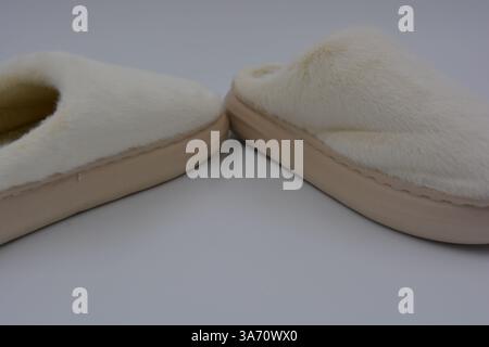 Belles et insolites choses pour femmes, chaussures de maison de tous les jours. Pantoufles douces chaudes blanches en fourrure épaisse synthétique avec semelles brunes épaisses et beiges. Banque D'Images