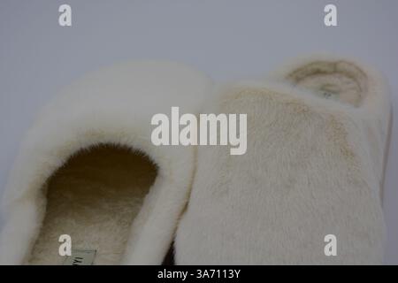 Belles et insolites choses pour femmes, chaussures de maison de tous les jours. Pantoufles douces chaudes blanches en fourrure épaisse synthétique avec semelles brunes épaisses et beiges. Banque D'Images
