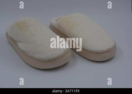 Belles et insolites choses pour femmes, chaussures de maison de tous les jours. Pantoufles douces chaudes blanches en fourrure épaisse synthétique avec semelles brunes épaisses et beiges. Banque D'Images