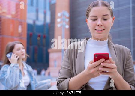 Jeunes femmes caucasiennes utilisant des smartphones dans un environnement urbain moderne Banque D'Images