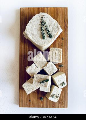 Cuisine asiatique. Tofu ou fromage de soja. Tranché de ​​and tofu cru entier, tofu blanc dur de caillé de soja sur une planche à découper en bois. Fromage végétal. Nourriture saine Banque D'Images