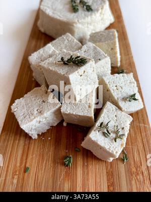 Cuisine asiatique. Tofu ou fromage de soja. Tranché de ​​and tofu cru entier, tofu blanc dur de caillé de soja sur une planche à découper en bois. Fromage végétal. Nourriture saine Banque D'Images