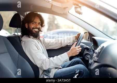 Homme indien souriant assis dans la voiture, regardant la caméra Banque D'Images