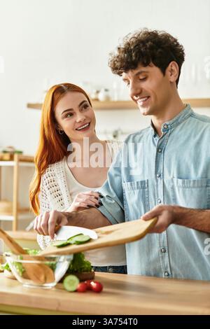 Un jeune couple profite d'un temps précieux ensemble alors qu'ils hachent des légumes frais pour un délicieux repas. Banque D'Images