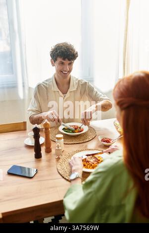 Dans un cadre cosy, un jeune couple profite d’un délicieux repas, savourant leur temps ensemble. Banque D'Images