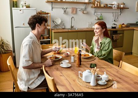 Un jeune couple profite de moments de qualité ensemble à la maison, partageant des sourires et un délicieux repas. Banque D'Images