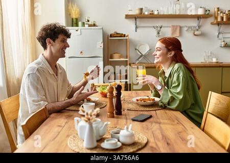 Jeune couple aime un délicieux repas à la maison, partageant des rires et des moments de qualité autour de la nourriture. Banque D'Images