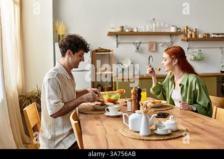 Jeune couple aime un repas confortable dans leur cuisine, célébrant l'amour et la convivialité. Banque D'Images
