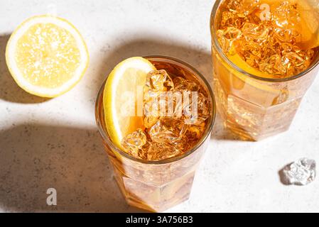 Thé glacé au citron. Verres de thé glacé sucré avec des tranches de citron et de la glace écrasée avec la lumière du soleil à la mode. Boisson fraîche d'été maison. Banque D'Images