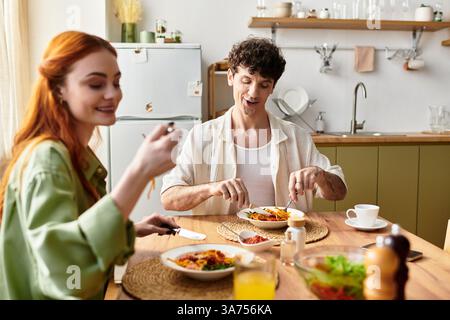 Un jeune couple profite d'un délicieux dîner à la maison, savourant chaque bouchée et riant ensemble. Banque D'Images