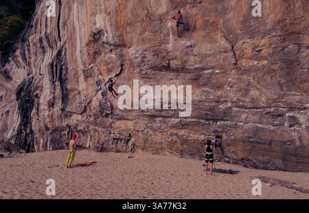 Les grimpeurs escaladent les superbes falaises calcaires de Tonsai, tandis que les gardiens veillent sur le sable Banque D'Images