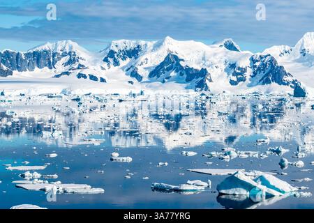 Superbes montagnes couvertes de neige reflétant dans l'eau de l'Antarctique. Banque D'Images