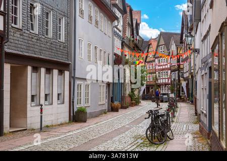 Fachwerk maisons le long de la rue pavée dans la vieille ville de Marburg Allemagne avec des vélos et des drapeaux colorés Banque D'Images