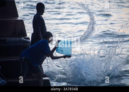 Deux enfants éclaboussant et jouant avec de l'eau à Baharia Hindi Beach à Zanzibar, Tanzanie Banque D'Images