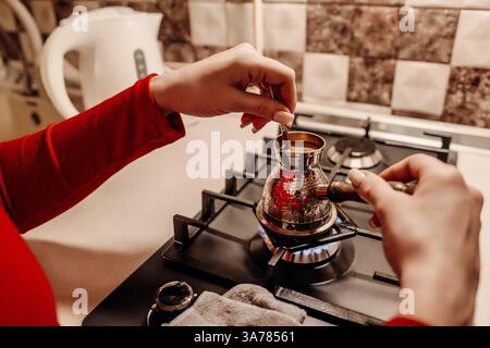 Café Brewing Turquie cuisinière cuisine : femme prépare le café traditionnel sur une cuisinière à gaz. Banque D'Images