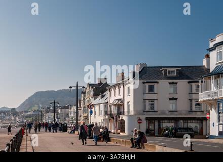 Promenade de Sidmouth au début du printemps avec des foules de gens marchant le long et assis avec la ville comme toile de fond. East Devon, Angleterre Royaume-Uni. Banque D'Images