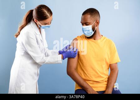 Médecin mettant un pansement sur un patient afro-américain après une injection de vaccin contre la grippe Banque D'Images