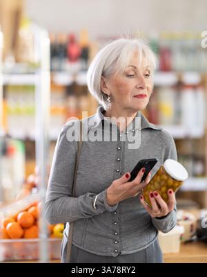 Femme âgée scannant le code qr pour les olives Banque D'Images