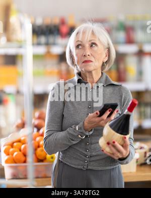 Femme âgée scannant le code qr du vin Banque D'Images