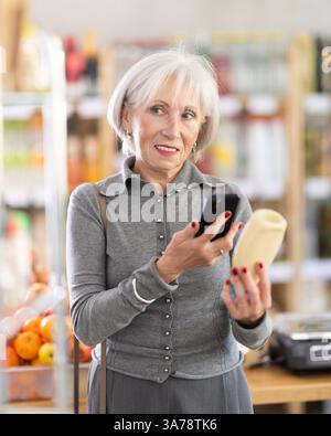 Femme âgée scannant le code qr pour la mayonnaise Banque D'Images