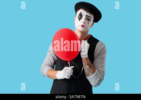 Pantomimiste masculin avec ballon sur fond bleu Banque D'Images