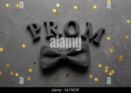 PROM mot avec confettis et noeud papillon sur fond grunge noir Banque D'Images