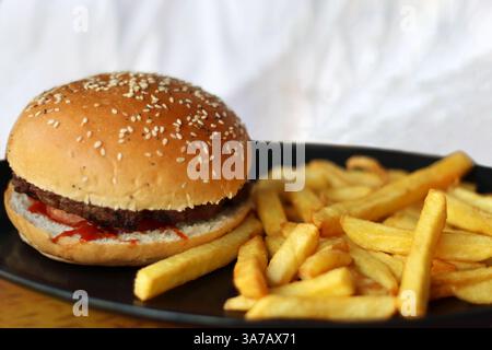Un hamburger avec un côté de frites sur un plateau. Banque D'Images