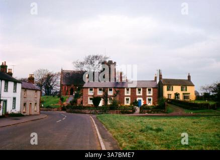 Une charmante photographie des années 1960 de Scotby Village, Cumbria, capturée sur un film de diapositives couleur 35mm original. Niché au cœur du village, l'image présente des cottages pittoresques en briques et en pierre le long de Scotby Village Road, avec l'église de grès rouge de la All Saints debout fièrement en arrière-plan. Banque D'Images