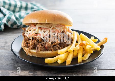 Sandwich au porc effiloché avec salade de coleslaw et frites sur la table en bois Banque D'Images