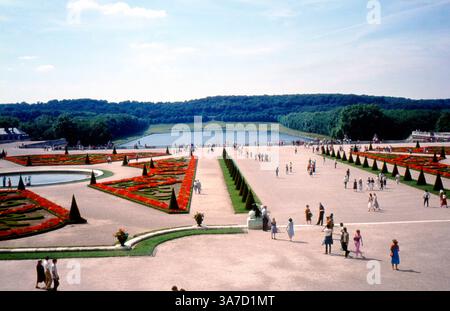 Une vue imprenable sur les jardins formels du château de Versailles en France, capturée dans les années 1980 Ces grands parterres arborent des parterres symétriques, des arbres ornementaux et des fontaines circulaires, tous conçus pour impressionner avec échelle et précision. Banque D'Images