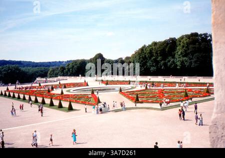 Une vue imprenable sur les jardins formels du château de Versailles en France, capturée dans les années 1980 Ces grands parterres arborent des parterres symétriques, des arbres ornementaux et des fontaines circulaires, tous conçus pour impressionner avec échelle et précision. Banque D'Images