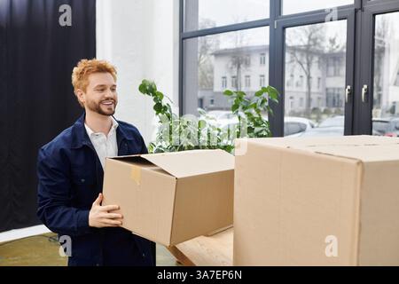 Un homme joyeux organise ses affaires pour un déménagement dans un espace bien éclairé. Banque D'Images