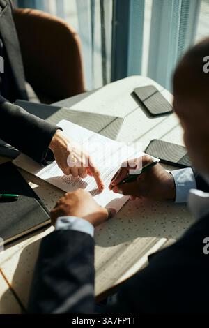 Vue à angle élevé du professionnel féminin des affaires aidant le client masculin signant le contrat à la table dans le bureau Banque D'Images