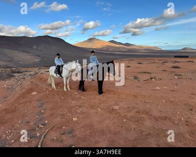 Deux jeunes hommes à cheval dans un paysage désertique. Banque D'Images